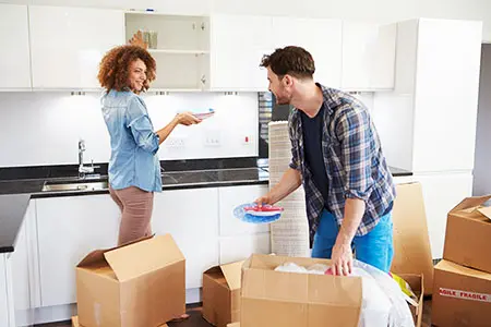 Couple unpacking box of kitchen supplies after moving