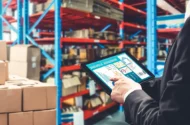 An employee using a tablet to monitor their supply chain in a warehouse.