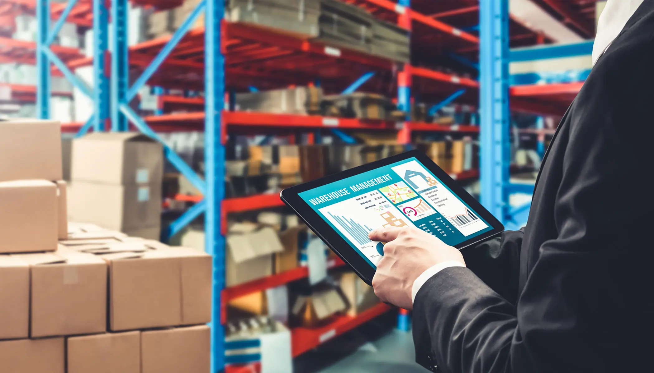 An employee using a tablet to monitor their supply chain in a warehouse.