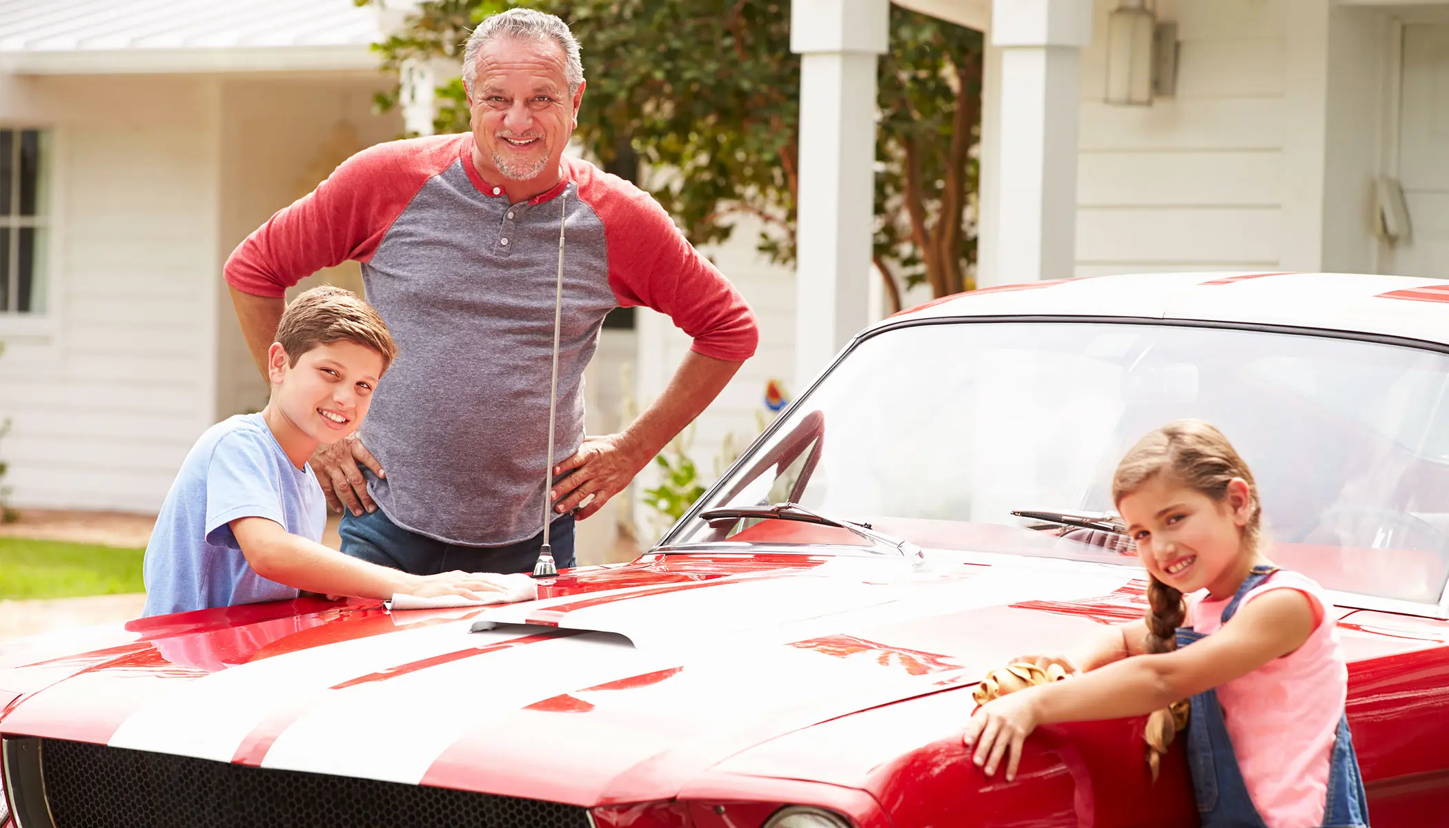 Grandfather and grandchildren with classic car
